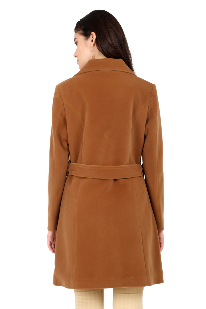 A back pose of a standing woman, wearing Trufit’s Long Dk. Camel Velvet coat with a lapel collar, button closure, belt, side pockets and skin bell bottom.